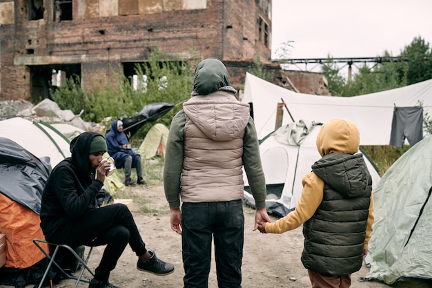 Back view of twow refugees standing in front of camp