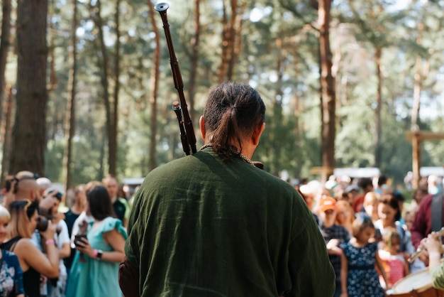 Back view of an unrecognizable musician in vintage costume playing bagpipes at an outdoor music folk festival Closeup selective focus