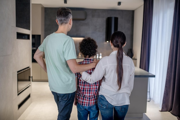 Back view of woman and man embracing boy