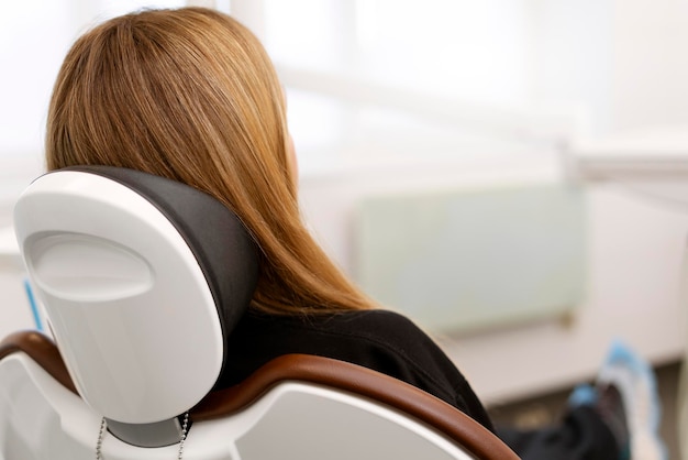 Back view of a woman sitting in a dental chair Bright spacious dental office comfortable dental chair