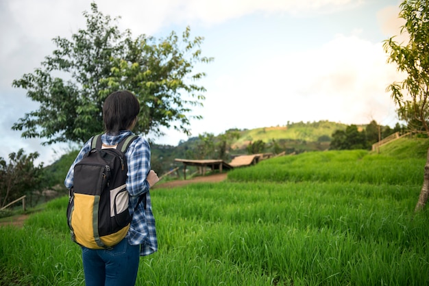 Back view of woman traveler with backpack stand on rice field in Chaing mai, Thailand.