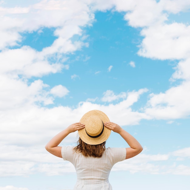 Back view of woman with hat admiring clouds in the sky