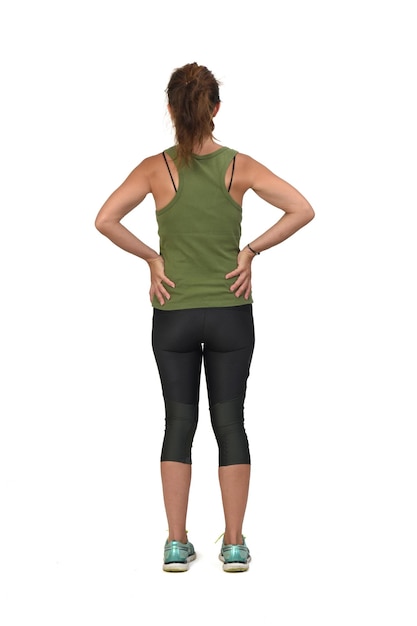 Back view of a woman with sportswear hands akimbo on white background