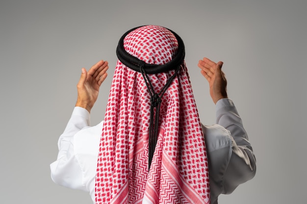 Back view of young Arab man standing on gray background