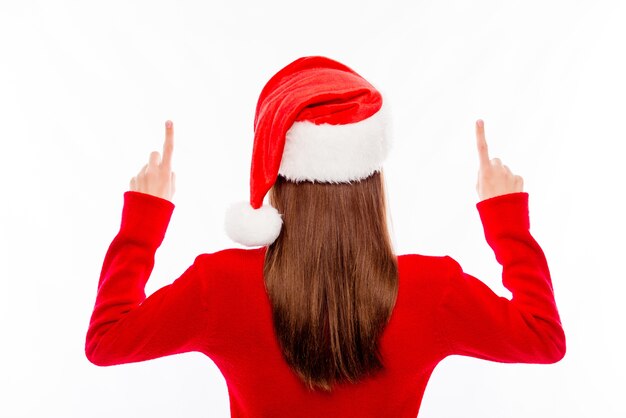 Back view of young brunette in santa hat gesturing up