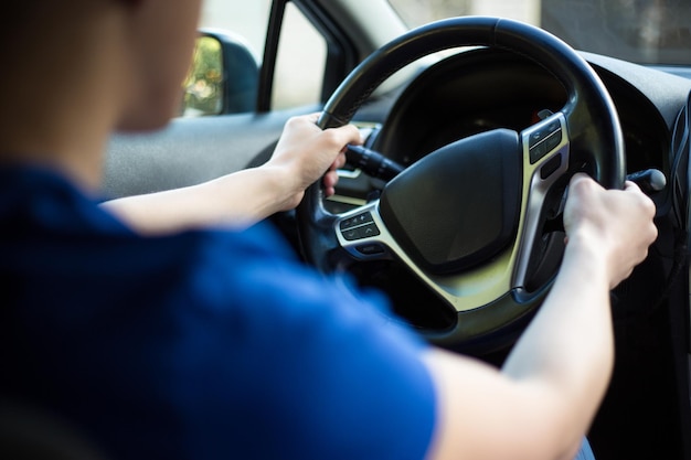 Back view of young male driver holding steering wheel