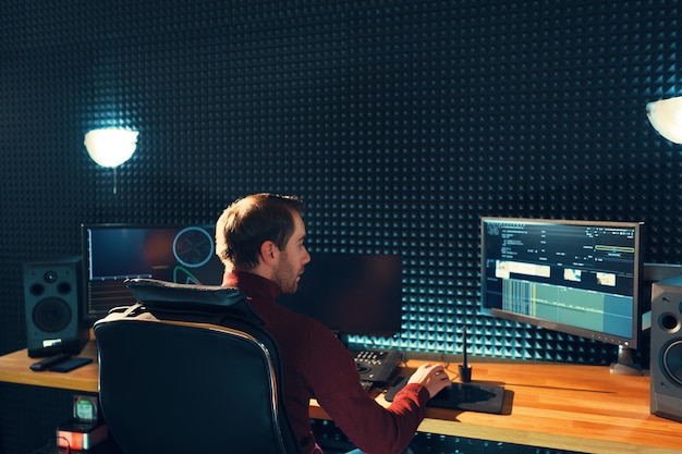 Back view of young man watching graphs on monitors