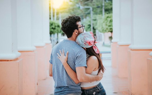 Back view of young woman hugging her boyfriend Back view of girl hugging her boyfriend outdoors Back view of happy couple hugging outdoors