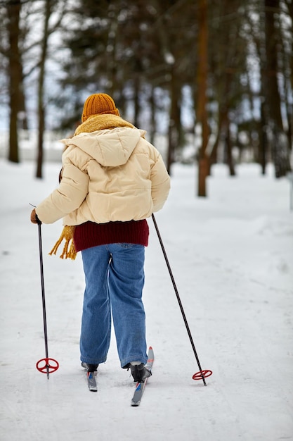 Back view at young woman skiing in winter forest and enjoying activity outdoors