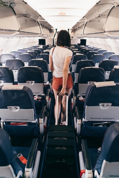 Back view of young woman walking the aisle on plane