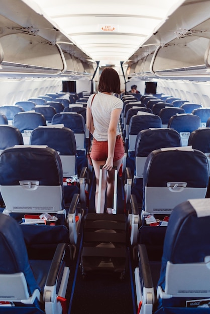 Back view of young woman walking the aisle on plane