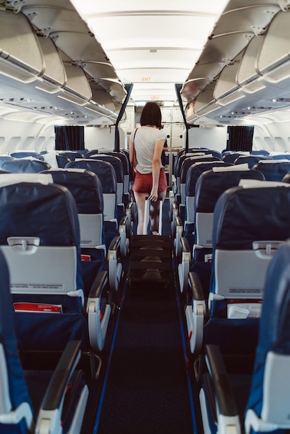 Back view of young woman walking the aisle on plane