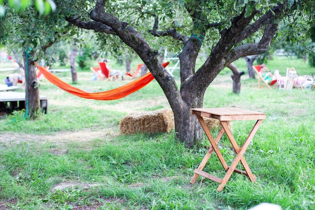 Back yard with hammock and wooden table for relaxing. Terrace, apple garden in summer, wooden table with haystack. wooden table on patio on an autumn day in village. relaxing in hammock in garden.