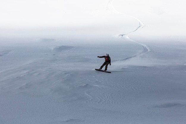 The backcountry snowboarder gracefully carves through the untouched powder snow leaving behind a trail of white fluff