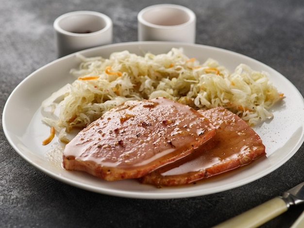 Backed Kasseler pork steak with sauerkraut Smoked pork lion Sliced smoked pork chop on wooden board