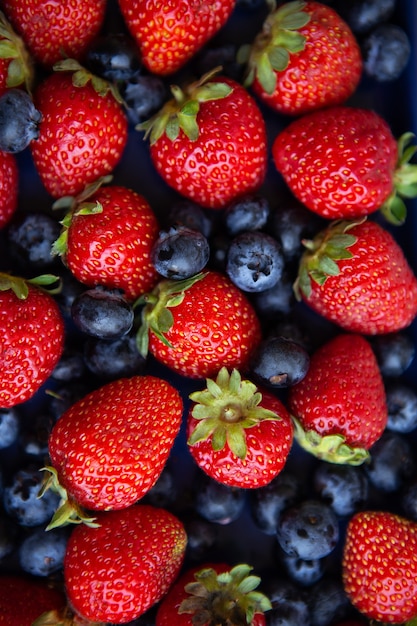 Background of assorted fresh berries of red juicy strawberries and blue blueberries close-up. View from above.