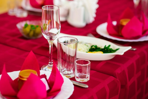 Background of beautiful served table with Red tablecloth and napkins white china gold cutlery spruce tree branches Top view Holiday setting Christmas mood