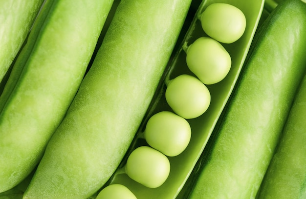 Background of closed pods of green peas and one open top view