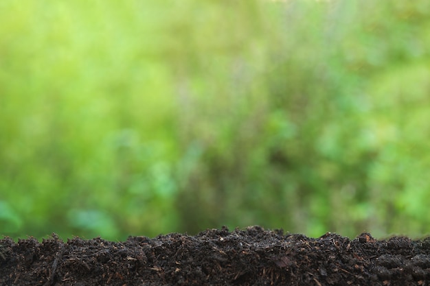 Background concept. Pile of soil on a green bokeh background with copy space.