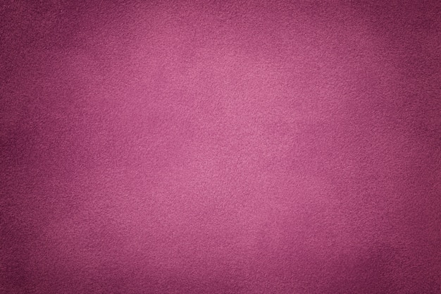 Background of dark purple suede fabric closeup. Velvet matt texture of wine nubuck textile