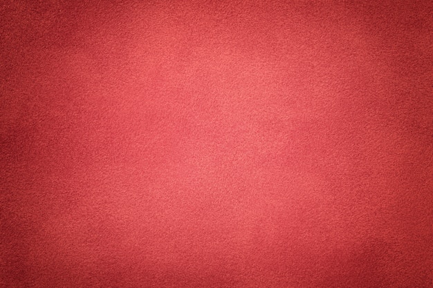 Background of dark red suede fabric closeup. Velvet matte texture