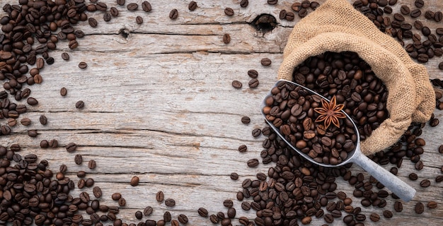 Background of dark roasted coffee beans with scoops setup on wooden background with copy space