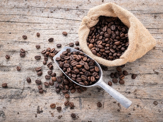 Background of dark roasted coffee beans with scoops setup on wooden background with copy space