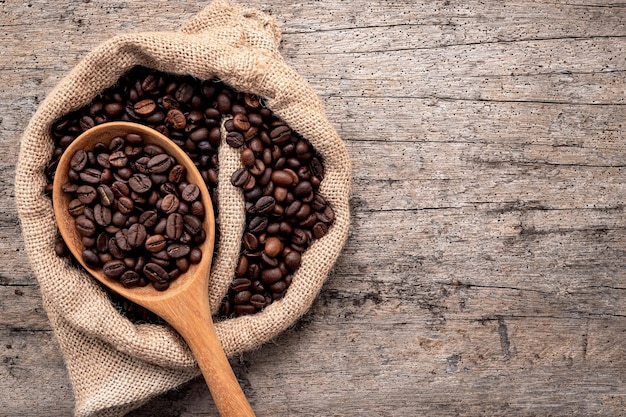 Background of dark roasted coffee beans with scoops setup on wooden background with copy space