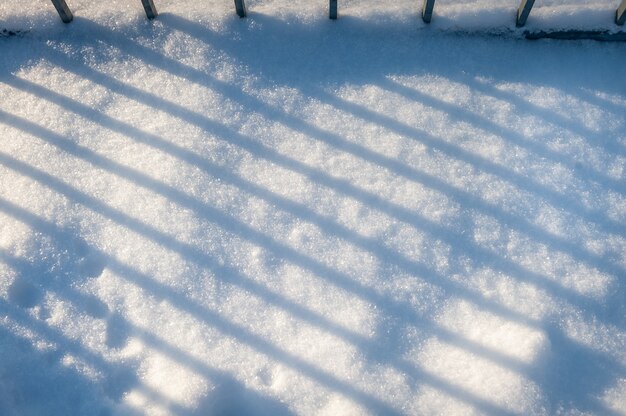 Background of fresh snow with stripes. Snow background with shadows.