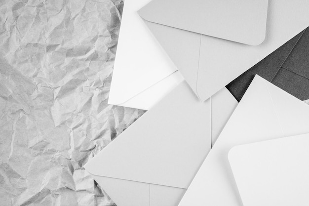 Background image of black white cardboard envelopes lying randomly on crumpled paper background. Top view. Copy space