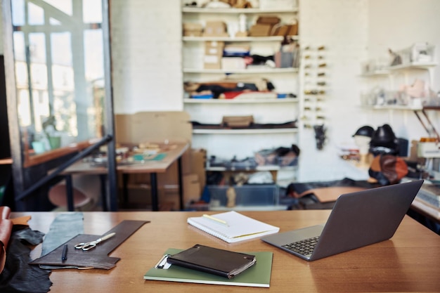 Background image of table with computer in leatherworking shop copy space