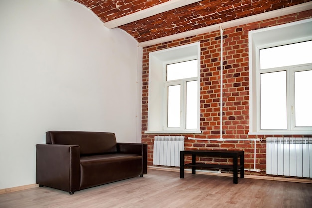 Background interior of room is designed in loft style with decorative red brick wall and furniture Industrial design grunge interior with large space