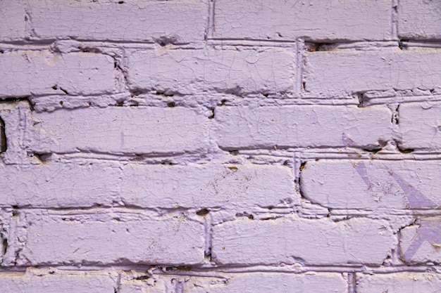 The background is made of purple and pink bricks with a wavy relief cracks holes and ditches Building material for decoration and decor in the style of a loft