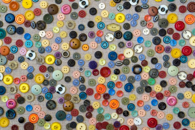 Background - multicolored plain buttons chaotically arranged on a rough canvas