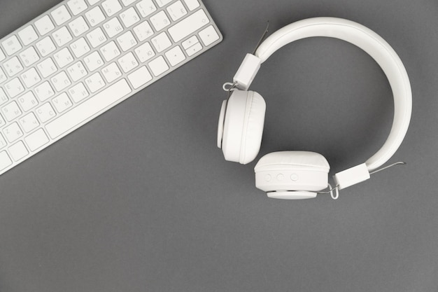 Background music or podcast with headphones and a computer keyboard on a gray table flat top view