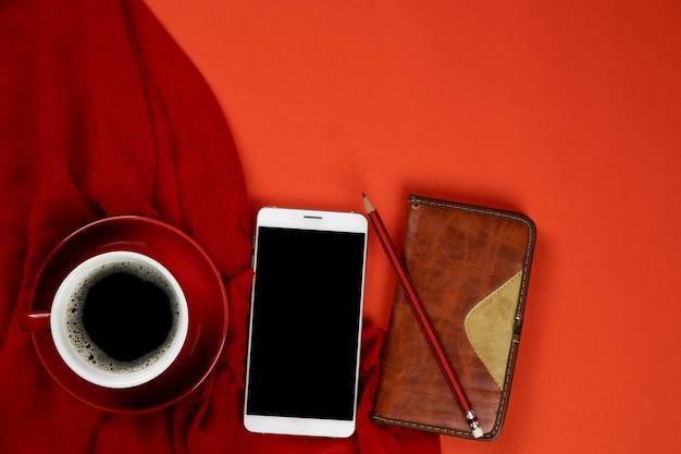 Background of red with smartphone, notebook and a cup of coffee