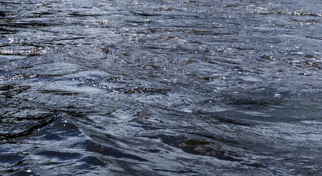 Background - river water with waves and whirlpools on a cloudy day