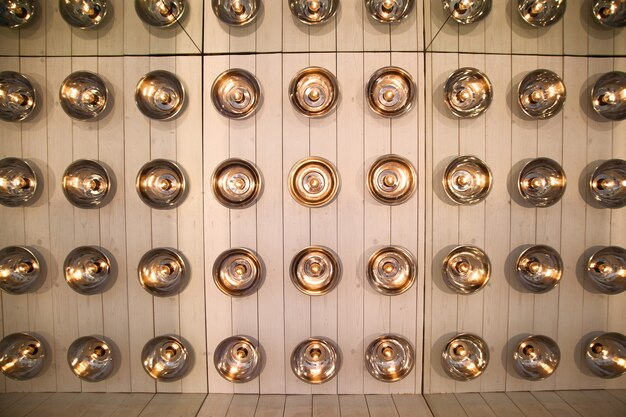 Background of round lamps on a wooden wall, reflected repeatedly in the mirrors