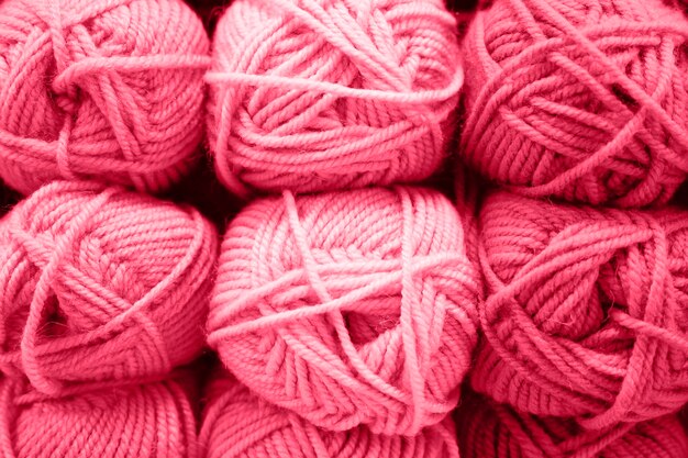 Background of rows skeins of fluffy wool yarn for knitting soft red pink purple hue colors toned in viva magenta trend color of the year 2023