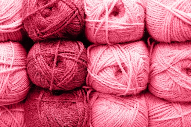 Background of rows skeins of fluffy wool yarn for knitting soft red pink purple hue colors toned in viva magenta trend color of the year 2023