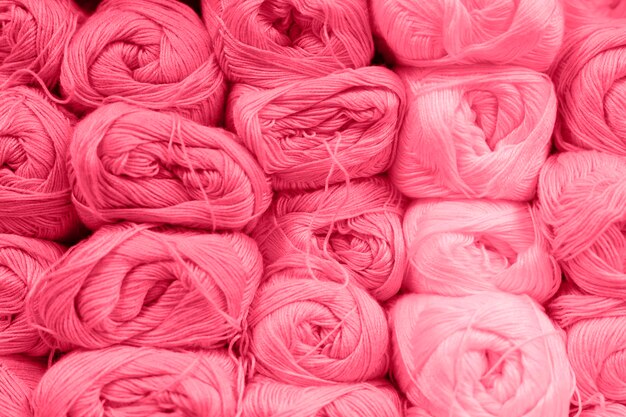 Background of rows skeins of fluffy wool yarn for knitting soft red pink purple hue colors toned in viva magenta trend color of the year 2023