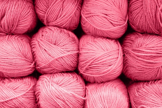 Background of rows skeins of fluffy wool yarn for knitting soft red pink purple hue colors toned in viva magenta trend color of the year 2023