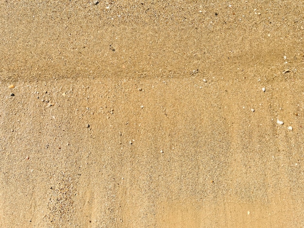 A background of sand small pebbles and flowing wave on the sea beach Summer vacation concept