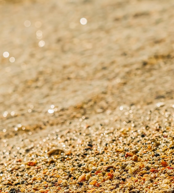 A background of sand small pebbles and flowing waves on the sea beach Summer vacation concept