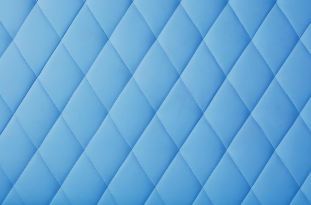 Background texture of pastel blue genuine leather soft tufted furniture or wall panel upholstery with deep diamond pattern close up