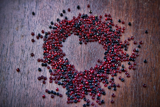 Background for Valentine's day. Heart shape in a  heap of beads. Wooden pattern. Retro style.