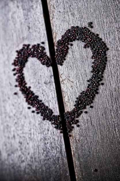 Background for Valentine's day. Heart shape in a  heap of beads. Wooden pattern. Retro style.