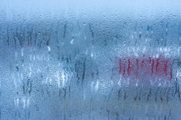 Background water drops on the glass wet window glass with splashes and drops of water and lime texture autumn background Condensation on the glass