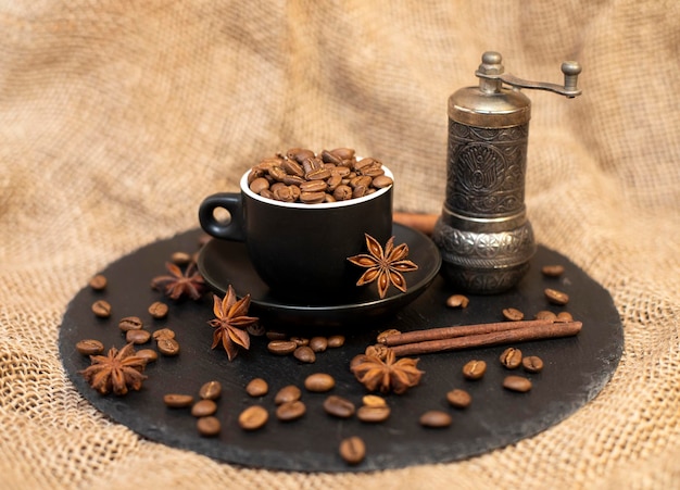 Background with coffee beans in a mug with cinnamon, star anise and coffee grinder