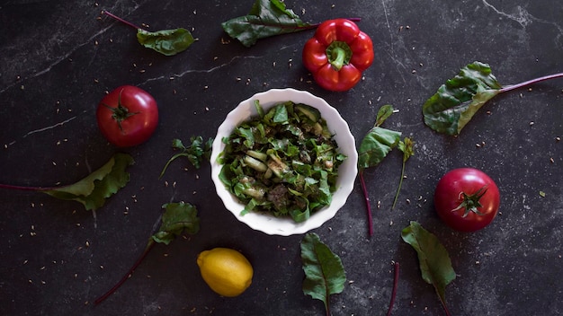 Background with food for vegetarians a plate with salads around vegetables on a dark background